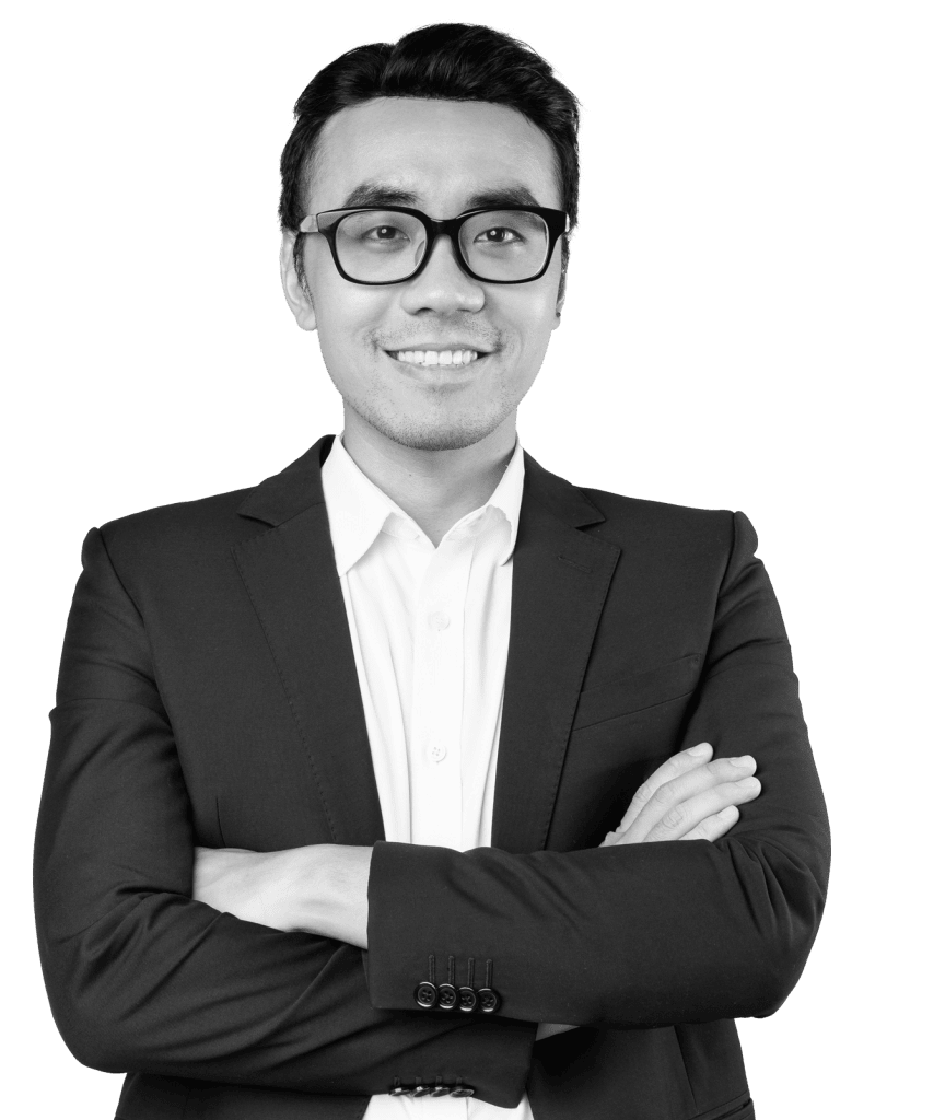 Man with glasses in a dark suit standing with his arms crossed and smiling
